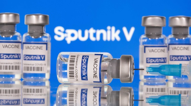 Vials labelled "Sputnik V Coronavirus COVID-19 Vaccine" and a syringe are seen in front of a Sputnik V logo in this illustration photo