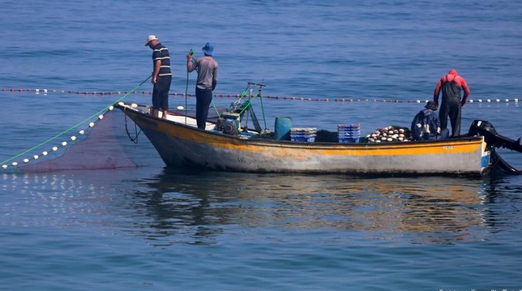 Palestinian fishermen paddle a boat at the sea during the sunset off the coast of the northern Gaza