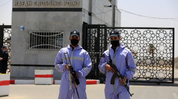 Members of Palestinian security forces wear protective gear as precaution against the coronavirus disease (COVID-19), stand guard at Rafah border crossing