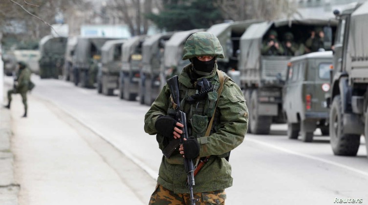 FILE PHOTO: Armed servicemen wait in Russian army vehicles outside a Ukranian border guard post in the Crimean town of Balaclava