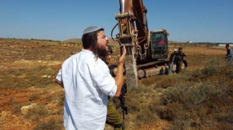مستوطنا يحرث أرضا بالأغوار الشمالية تمهيدا للاستيلاء عليها